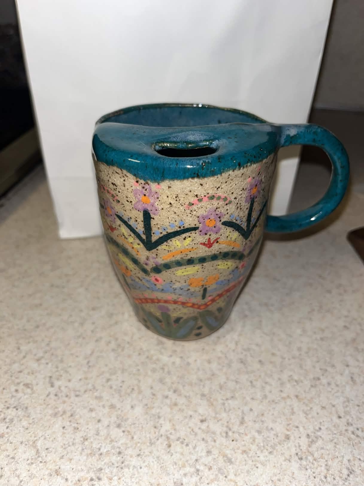 Mug with blue top and lip cover. Features flower designs.