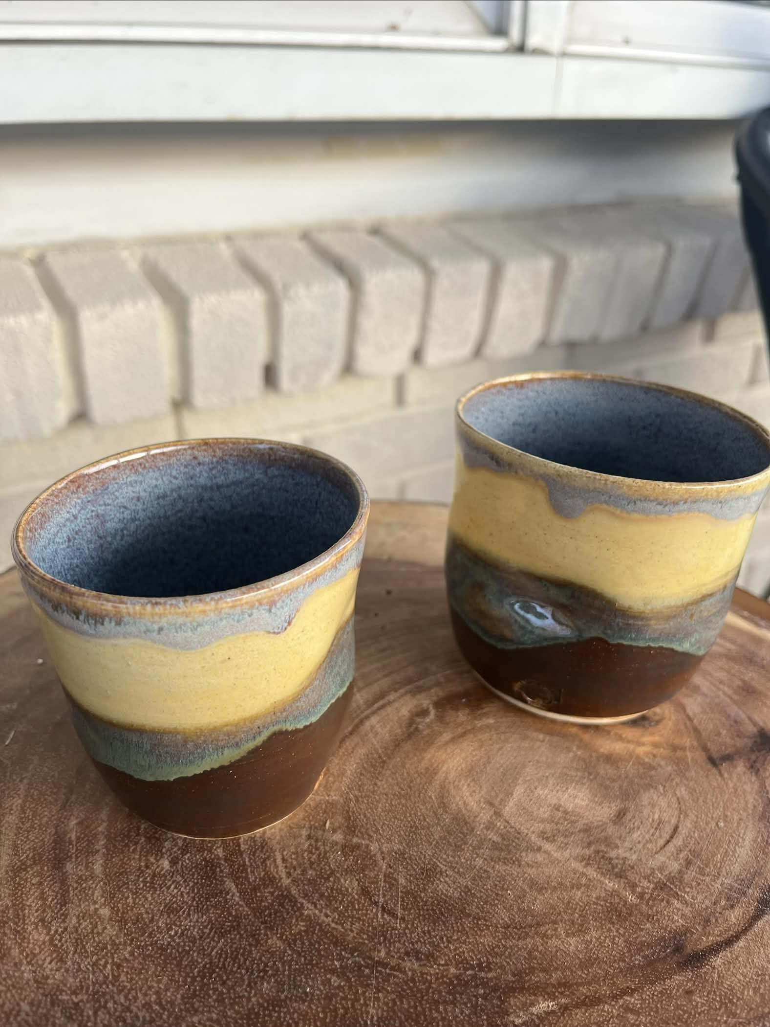 Two brown, yellow, and blue small tumblers